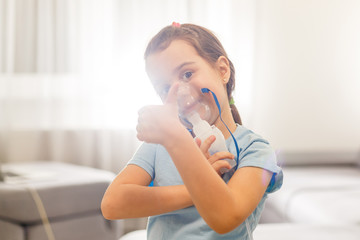 Little girl in a mask, treatments respiratory tract with a nebulizer at home