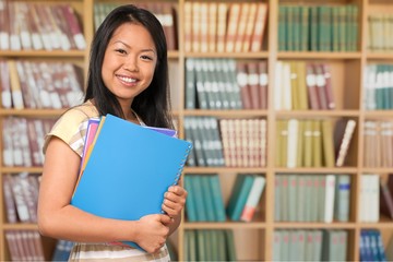 Young female student on blurred library background