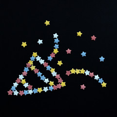 Smiley firework folded from sugar pastry stars on a black background with copyspace on square shape