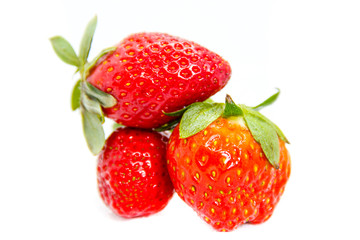Several red strawberries with leaves on a white background