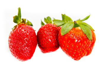 Several red strawberries with leaves on a white background