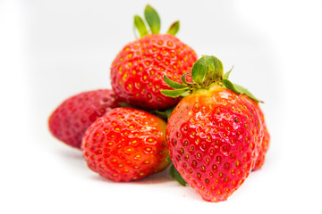 Several red strawberries with leaves on a white background
