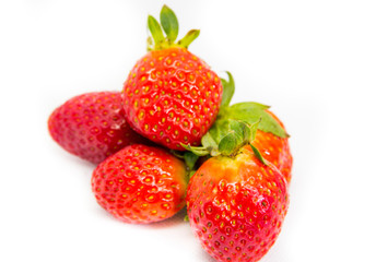 Several red strawberries with leaves on a white background