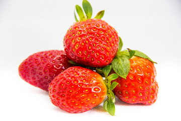 Several red strawberries with leaves on a white background