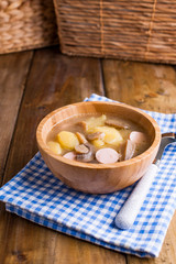 soup with sausages and potatoes on a wooden background in a bowl. Traditional German rustic soup. Rustic style photo. Free space for text.
