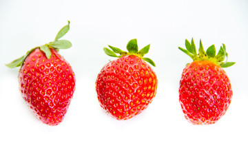 Several red strawberries with leaves on a white background