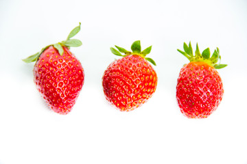 Several red strawberries with leaves on a white background