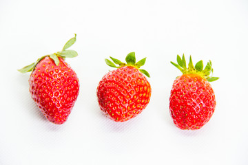 Several red strawberries with leaves on a white background