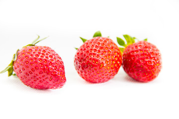Several red strawberries with leaves on a white background