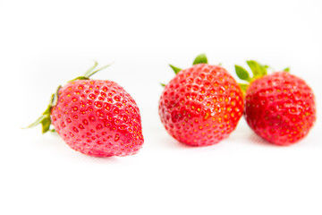 Several red strawberries with leaves on a white background