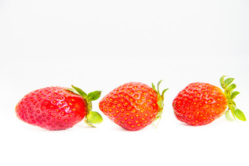 Several red strawberries with leaves on a white background