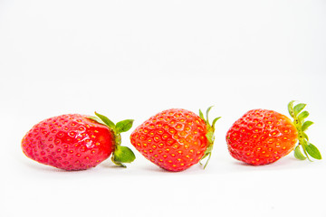 Several red strawberries with leaves on a white background