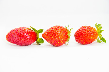 Several red strawberries with leaves on a white background