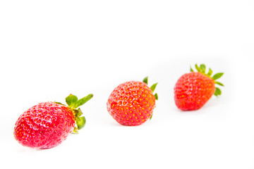 Several red strawberries with leaves on a white background