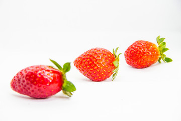 Several red strawberries with leaves on a white background