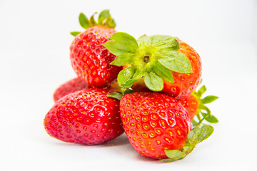 Several red strawberries with leaves on a white background