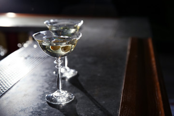 Glasses of martini cocktail with olives on bar counter. Space for text