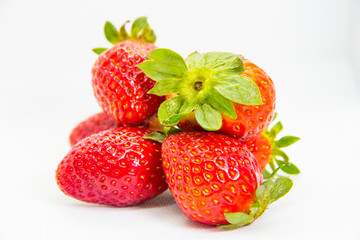 Several red strawberries with leaves on a white background