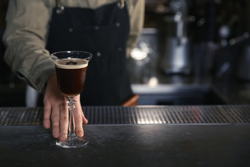 Barman serving espresso martini cocktail at counter, closeup. Space for text