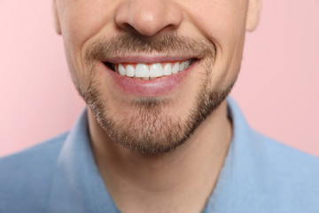 Smiling man with perfect teeth on color background, closeup