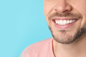 Obraz premium Smiling man with perfect teeth on color background, closeup. Space for text