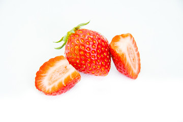 Whole and cut in half red strawberry and cut with leaves on white background
