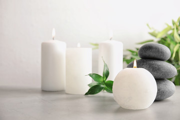 Beautiful spa composition with candles and stones on table, space for text