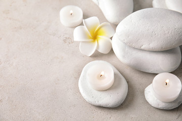 Beautiful spa composition with candles and stones on light background, space for text