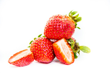 Whole and cut in half red strawberry and cut with leaves on white background