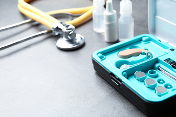 Hearing aid case and other medical objects on grey table. Space for text