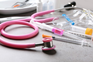Stethoscope and syringes on grey table. Medical objects