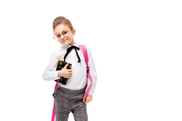 Back to school. Beautiful little girl dressed like a School girl - in white shirt and gray pants, rounded glasses, hold a book with school bag and posing like model. Isolated on white background.