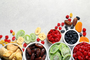 Bowls of different dried fruits on grey background, top view with space for text. Healthy food