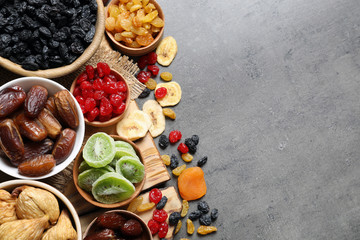 Bowls of different dried fruits on grey background, top view with space for text. Healthy food