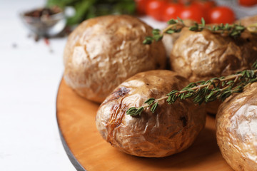 Board with tasty baked jacket potatoes on table, closeup