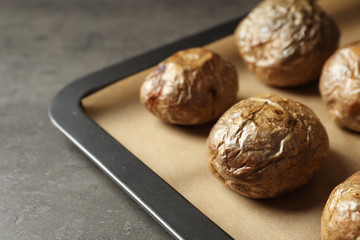 Tray with baked jacket potatoes on table, closeup. Space for text
