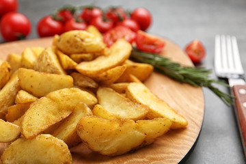 Plate with tasty baked potato wedges on table, closeup