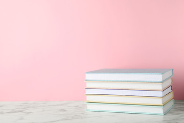 Stack of hardcover books on table against color background, space for text