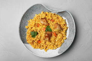Plate with delicious rice pilaf on grey background, top view