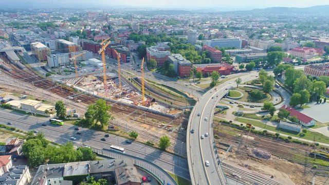 Panorama of Krakow city with a multi-level intersection, railroad tracks and cranes at the construction of a skyscraper. Aerial view from drone, from above