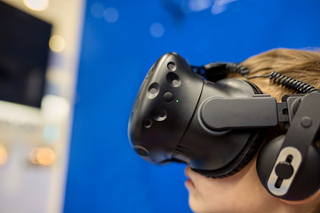 modern technology, gaming and people concept - boy in virtual reality headset or 3d glasses playing videogame at game centre