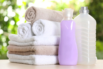 Obraz na płótnie Canvas Soft bath towels and laundry detergents on table against blurred background