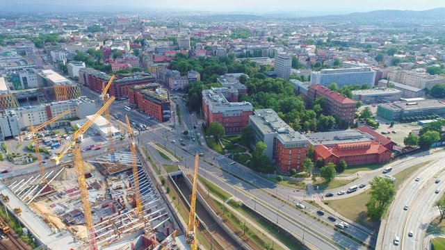 Panorama of Krakow city with a multi-level intersection, railroad tracks and cranes at the construction of a skyscraper. Aerial view from drone, from above
