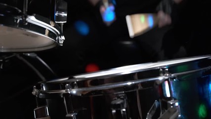 Girl drummer banging on a drum kit on stage.