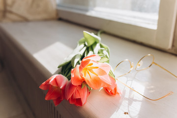 Tender pink fresh tulips and eye glasses on wooden branch