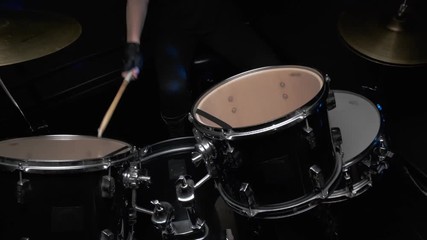 Girl drummer banging on a drum kit on stage.
