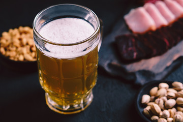 beer and snacks. bar table. restaurant, pub, food concept. delicious craft unfiltered drink, salted nuts and meat appetizers set- ham, sausages and jerky. friday party atmosphere, brewery background
