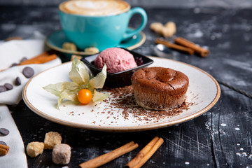 Chocolate lava cake Molten with ice cream on plate and cappuccino. Balls of ice cream in cup . Dark black background.