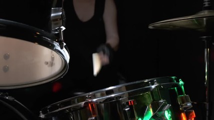 Girl drummer banging on a drum kit on stage.