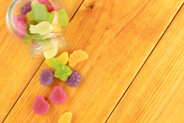 colored gummy fruit candy spilled, on a orange wooden table